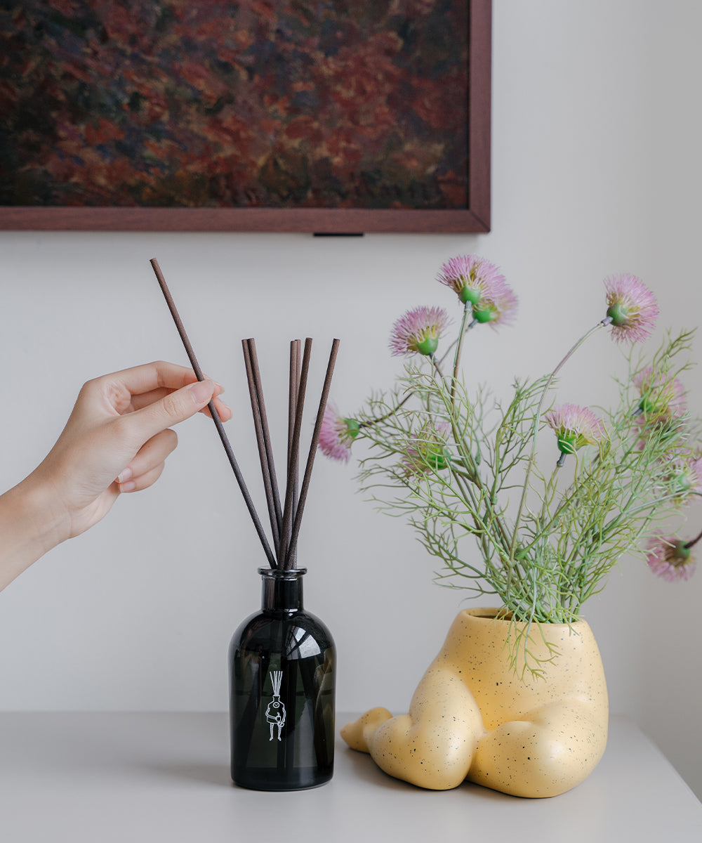 hand placing reed sticks into reed diffuser bottle