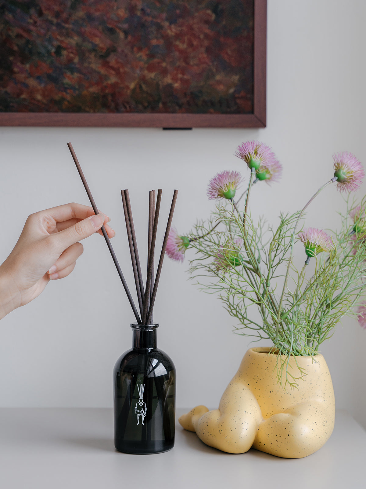 hand placing reed sticks into reed diffuser bottle