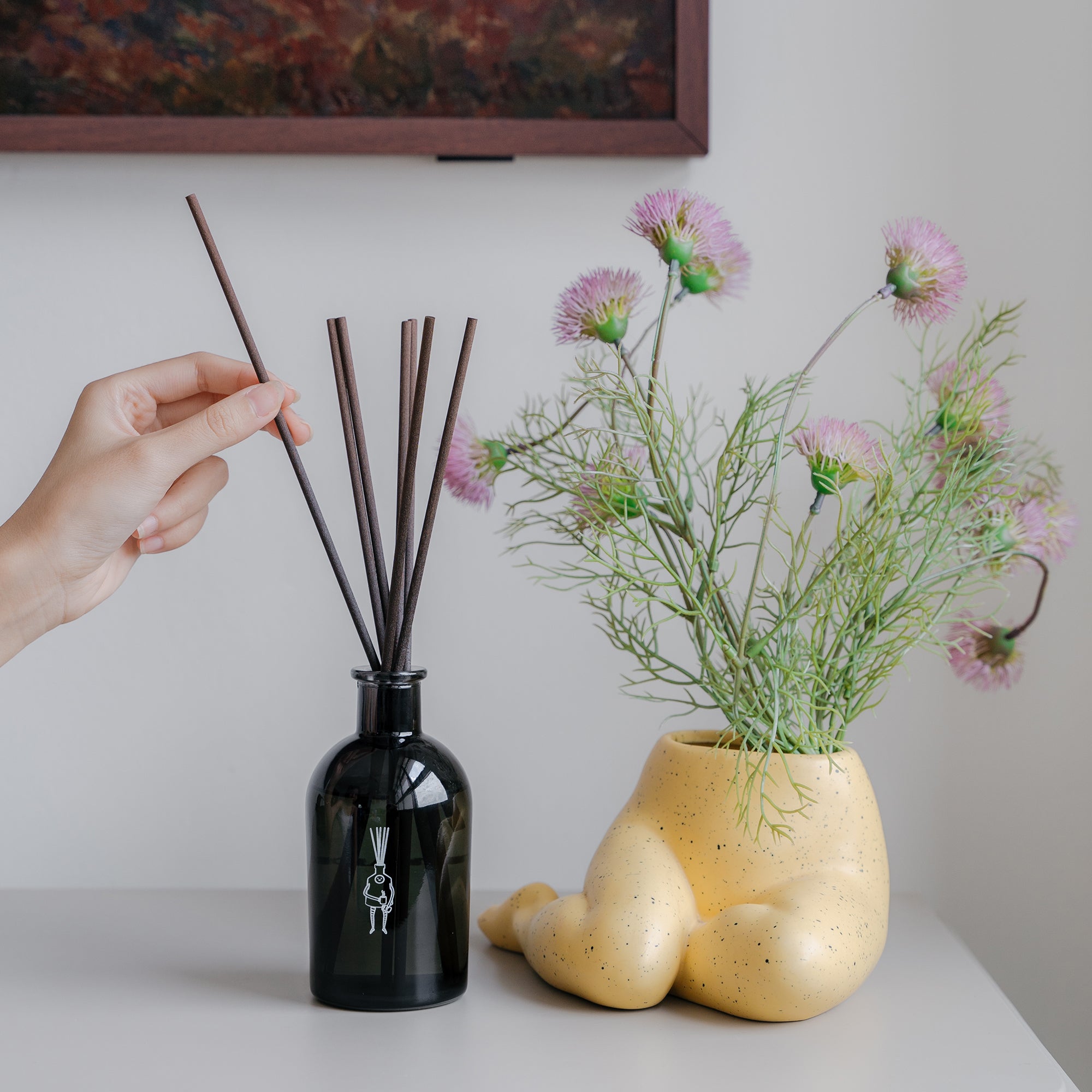 hand putting reed sticks into reed diffuser on tv console