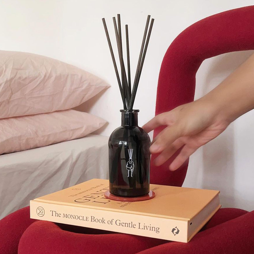 hand reaching out to pretty major home fragrance diffuser on book